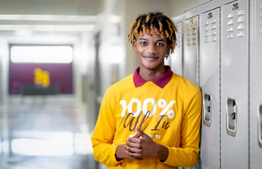 Male student smiling in a school hall looking at the camera.