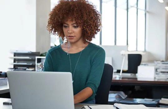 Uma designer sentada à mesa usando um Surface Laptop.