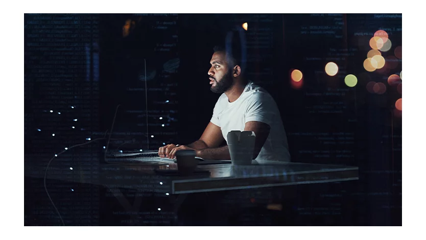 Programmer working on a computer in an office at night.