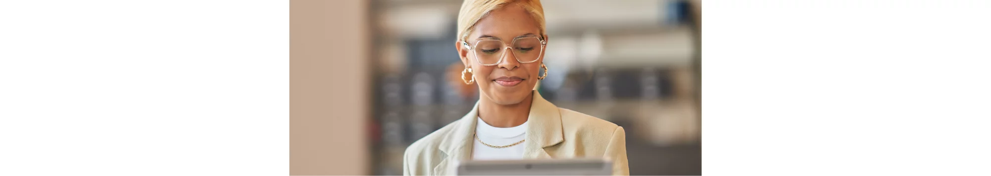 Una mujer con gafas sonríe y mirando una tableta