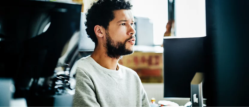 Una persona mirando a su equipo; la imagen se ha tomado desde una vista lateral