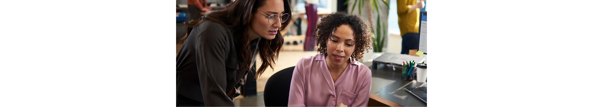 Dos mujeres mirando la pantalla de un equipo en una oficina.