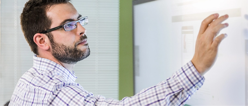 Una persona con gafas está usando un monitor de pantalla táctil