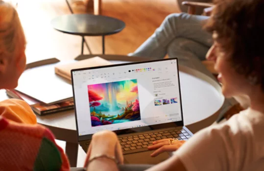 Due persone sedute davanti a un portatile sul quale è visualizzata l'app Paint