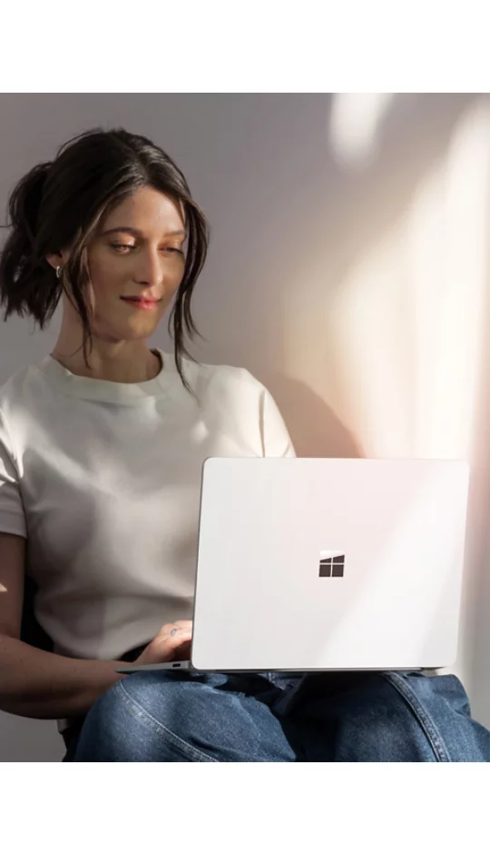 Una persona seduta digita su un dispositivo Surface Laptop Platino da 13,8 pollici.