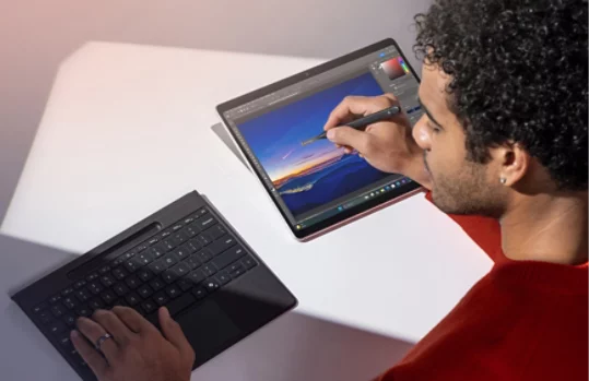 取り外した状態の Surface Pro Flex キーボードとスリム ペンを使用して、Surface Pro で写真を編集する人。