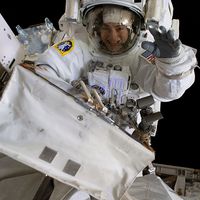 October 18, 2019. NASA astronaut Jessica Meir waves at the camera during a spacewalk with fellow NASA astronaut Christina Koch (out of frame). They ventured into the vacuum of space for seven hours and 17 minutes to swap a failed battery charge-discharge unit (BCDU) with a spare during the first all-woman spacewalk. The BCDU regulates the charge to the batteries that collect and distribute solar power to the orbiting lab's systems.