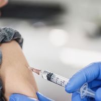 Young boy receiving a vaccine shot (child, vaccines, vaccinations, health care).