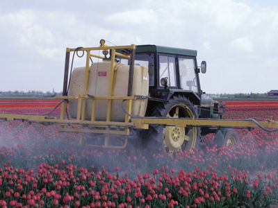 Farm machinery spraying pesticides on a crop.