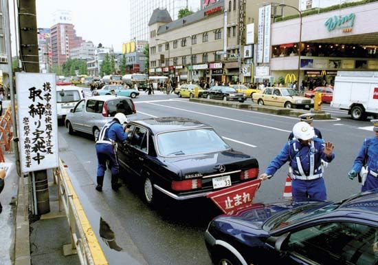 Officers of the Metropolitan Police Department in Tokyo, Japan, checking for unlawful activities such as the use of a mobile phone while driving.