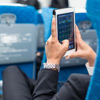 Businessman using tablet phone on airplane