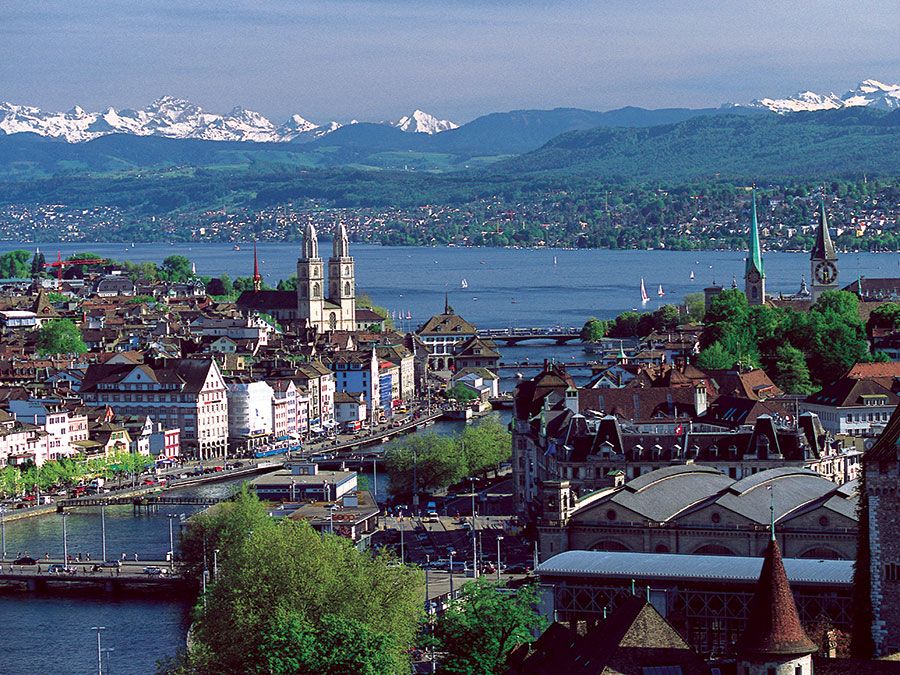 The twin spires of the Grossmunster are a distinctive feature of Zurich's cityscape: the popular panoramic view shows Zurich Downtown Switzerland, with Lake Zurich and the snow-capped Alps in the background.