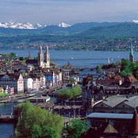 The twin spires of the Grossmunster are a distinctive feature of Zurich's cityscape: the popular panoramic view shows Zurich Downtown Switzerland, with Lake Zurich and the snow-capped Alps in the background.