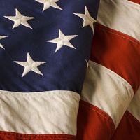 Close-up of a weathered, old American flag of the United States of America, used as a patriotic decoration on Fourth of July (Independence Day), Memorial Day, Veterans Day, and other national holidays.