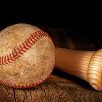 An old worn baseball and wood bat