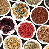 Herbal teas in white porcelain dishes over a bamboo background.