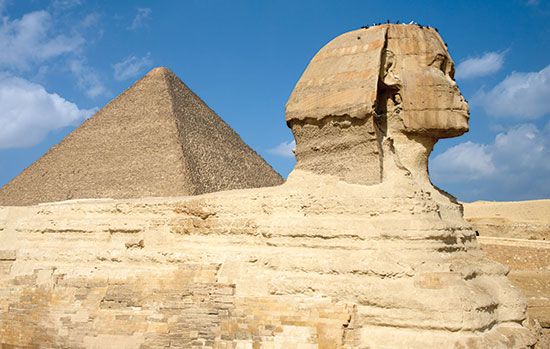 Side view of the Sphinx with the Great Pyramid of Khufu (Cheops) rising in the background at Giza, Egypt.