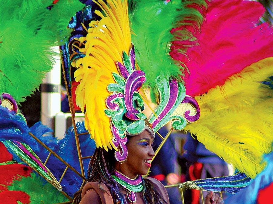 A woman with a brightly-colored feather headdress and costume, during a Carnival parade in Rio de Janeiro. Rio Carnival. Brazil Carnival.