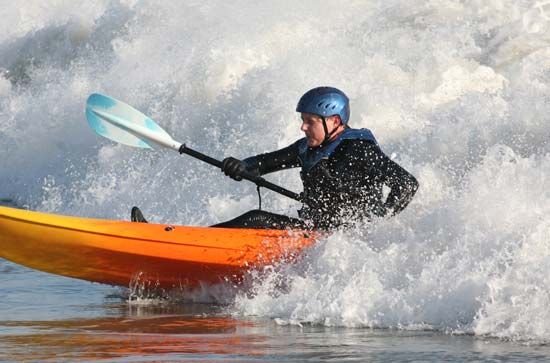 An open-water kayaker paddling through ocean waves.