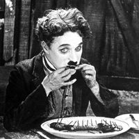 The Gold Rush (1925) Charlie Chaplin as The Tramp eating his meal made from his boot in a scene from the silent film. Silent movie comedy written, directed and produced by Charlie Chaplin