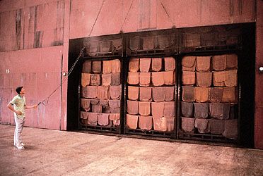 sheets of natural rubber hanging from racks in a smoke room for final drying