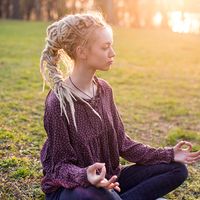 Young woman meditating in nature. About 20 years old, Caucasian female. dreadlocks