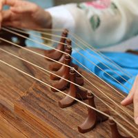 A woman wearing a hanbok plays the traditional Korean musical instrument kayagum (gayageum).