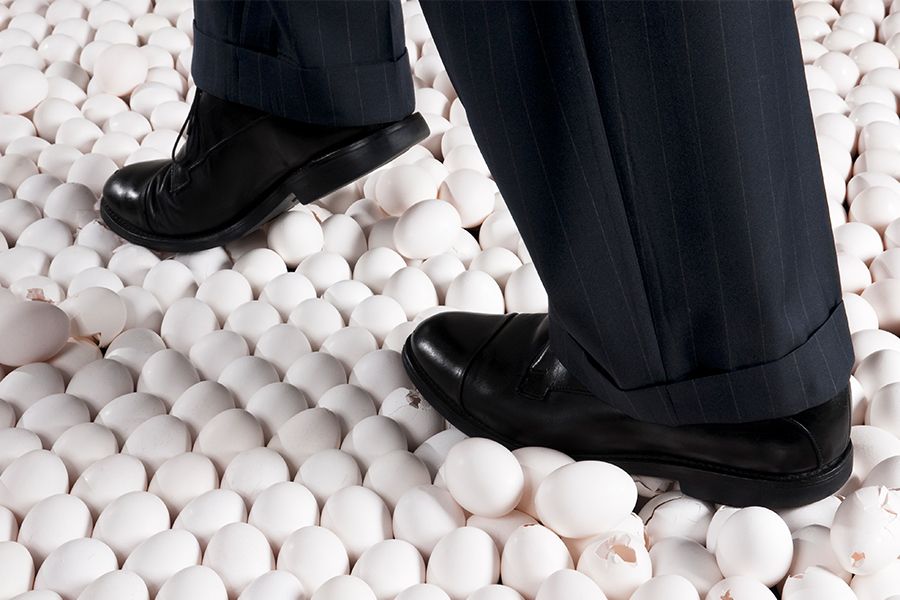 Man in Suit Walking on Eggshells. Idiom egg shell figure of speech