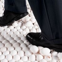 Man in Suit Walking on Eggshells. Idiom egg shell figure of speech