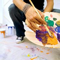 Close-up of a palette held by a man. Mixing paint, painting, color mixing.