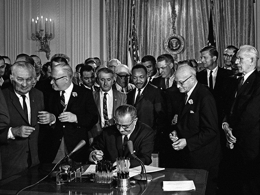 President Lyndon B. Johnson (Lyndon Johnson) signs the 1964 Civil Rights Act as Martin Luther King, Jr., others look on East Room, White House, Washington, D.C., July 2, 1964.