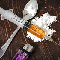 Drug syringe and cooked heroin on spoon