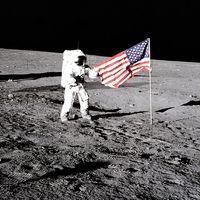 Apollo 12 astronaut Charles "Pete" Conrad stands beside the U.S. flag after is was unfurled on the lunar surface during the first extravehicular activity (EVA-1) Nov. 19, 1969. Footprints made by the crew can be seen in the photograph.