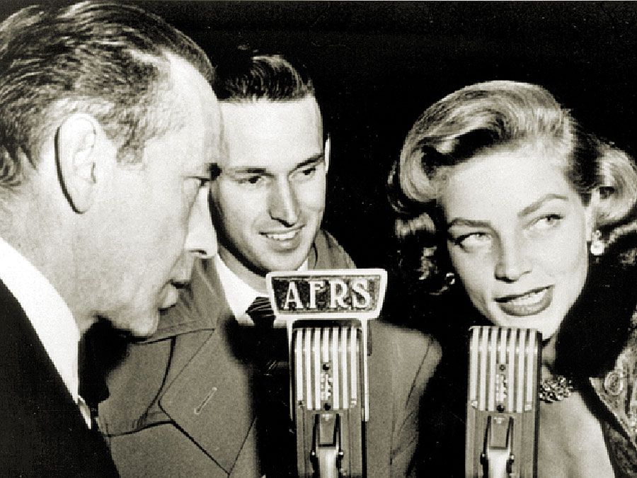 Armed Forces Radio Services broadcaster Jack Brown interviews Humphrey Bogart and Lauren Bacall for broadcast to troops overseas during World War II.