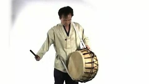 See a man playing a Korean puk a double-headed barrel drum