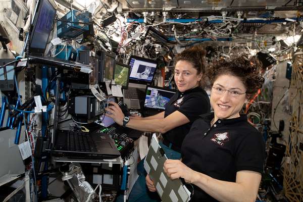 November 15, 2019.  NASA astronauts (from left ) Jessica Meir and Christina Koch are at the robotics workstation controlling the Canadarm2 robotic arm to support the first spacewalk to repair the Alpha Magnetic Spectrometer (AMS), the International Space Station's cosmic particle detector. Astronauts Luca Parmitano of ESA (European Space Agency) and Andrew Morgan of NASA worked six hours and 39 minutes in the vacuum of space during the first of at least four planned AMS repair spacewalks.