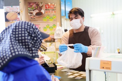 買いに来た女性（左）に揚げたての総菜を手渡す店主の藤田真也さん＝石川県輪島市で2024年3月1日午前10時57分、吉田航太撮影