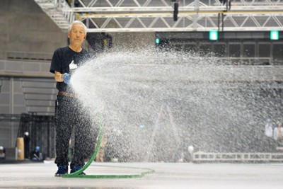 水をまいてアイスショーのリンク作りを行う高橋二男さん＝千葉市美浜区の幕張イベントホールで2024年5月21日、手塚耕一郎撮影