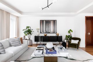 Lancer Square by 1508 features a white sofa to the left, a white rug, a marble table with books on display, a black side board.