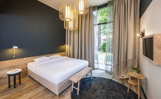 Bedroom in neutral tones with dark grey highlights, art deco chair and lights