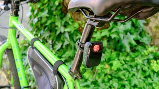 Trek CarBack Radar Rear Bike Light shown mounted on the seat post of a green bike with green foliage out of focus in the background