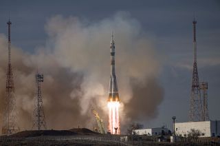 a rocket launches under a cloudy evening sky above a plume of fire of smoke