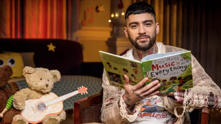 Former One Direction star Zayn Malik sits next to a teddy bear holding a toy guitar to read a &quot;Bedtime Story&quot; on CBeebies