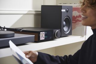 A Cambridge streaming amplifier sandwiched between a turntable and speaker