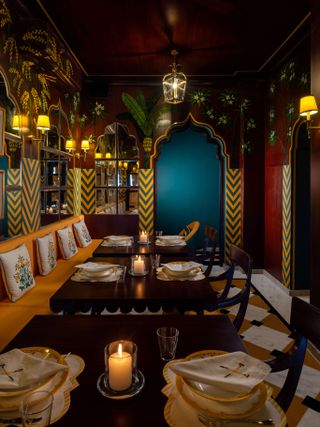 Three wooden tables with traditional Indian crockery and candles