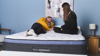 A Tom&#039;s Guide Sleep Editor and a mattress tester sit and lie down on a hybrid mattress to see how comfortable and supportive it feels