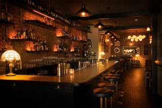 inside shot of a bar with stools alongside it, a london cocktail bar