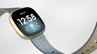 Light blue and gold Fitbit Versa 3 on neutral background