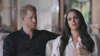 Prince Harry looking at Meghan Markle while she talks to the camera in Harry & Meghan.