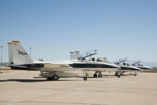 three white fighter jets on a runway in the desert